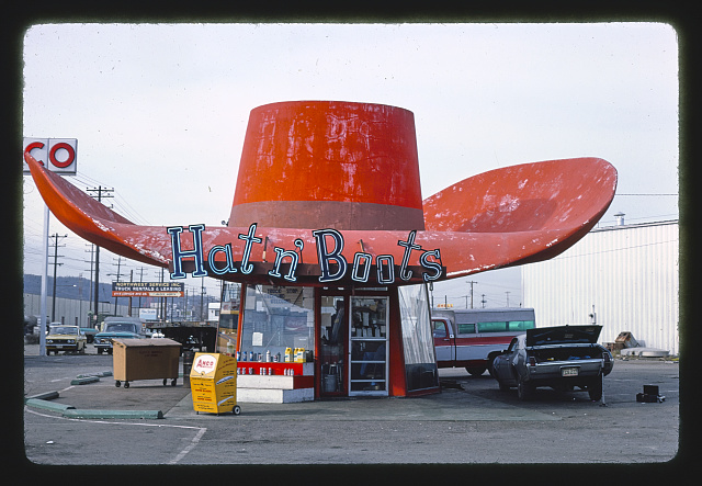 A small service station whose red roof is in the shape of a cowboy hat